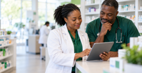 Physician and pharmacist reviewing information together at a pharmacy counter.