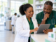 Physician and pharmacist reviewing information together at a pharmacy counter.